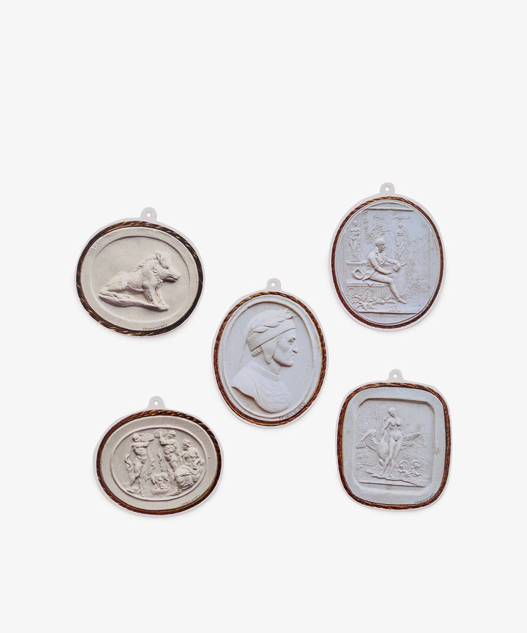 Introducing the Intaglio Tages, Set of 5—five oval medallions featuring classical relief designs of human and animal figures, artfully arranged in a cluster on a white background. Crafted from heavy cardstock, these elegant pieces make unique gift tags adorned with beautiful classical imagery.