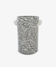 The Celine Wine Cooler is a tall cylindrical ceramic piece crafted from black and white clay, featuring intricate floral or feather-like patterns and two small white side handles, set against a plain white background.