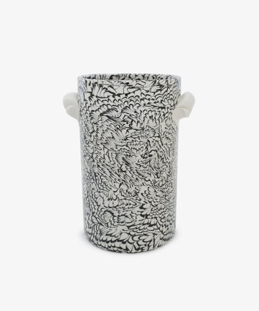 The Celine Wine Cooler is a tall cylindrical ceramic piece crafted from black and white clay, featuring intricate floral or feather-like patterns and two small white side handles, set against a plain white background.