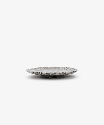 The Celine Serving Plate is a shallow, round handcrafted ceramic plate featuring a black and white abstract pattern reminiscent of Aptware, shown against a plain white background.