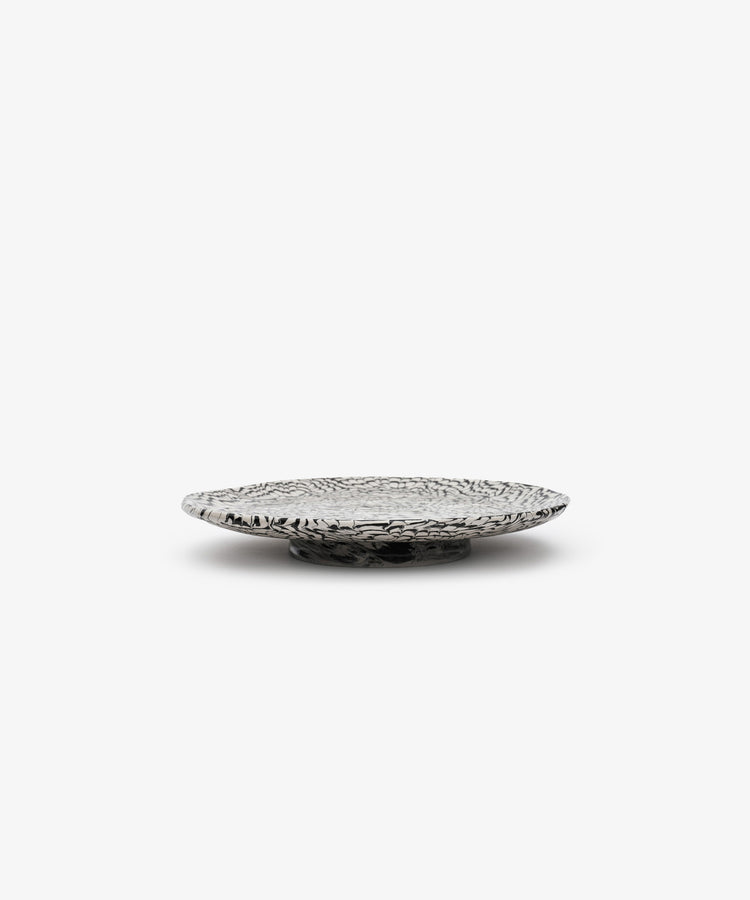 The Celine Serving Plate, a low, round, handcrafted silver dish with a textured, patterned surface, sits on a plain white background.