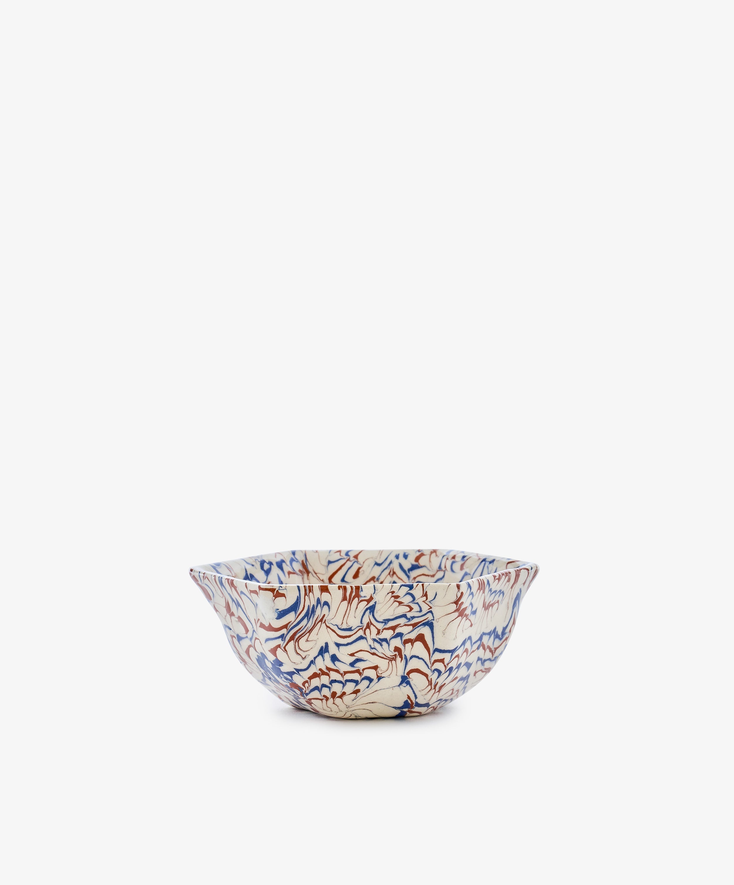 The Celine Snack Bowl is a marbled ceramic piece with a wavy rim, showcasing a red and blue abstract pattern on a white background, displayed against a plain white backdrop.