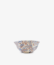 The Celine Snack Bowl is a marbled ceramic piece with a wavy rim, showcasing a red and blue abstract pattern on a white background, displayed against a plain white backdrop.