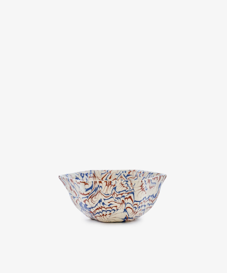 The Celine Snack Bowl is a marbled ceramic piece with a wavy rim, showcasing a red and blue abstract pattern on a white background, displayed against a plain white backdrop.