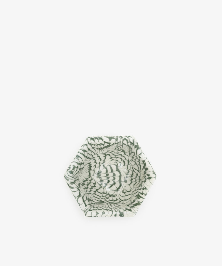 The Celine Snack Bowl is a small hexagonal dish inspired by aptware, showcasing a green and white swirling feather-like pattern centered on a crisp white background.