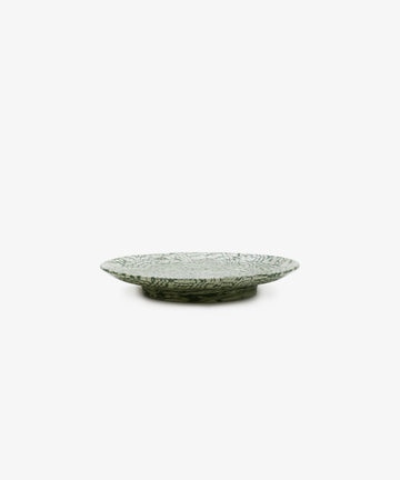 The Celine Serving Plate is a shallow, round ceramic dish featuring a green and white marbled leaf pattern, displayed against a plain white background.