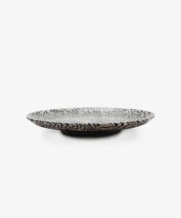 The Celine Serving Platter is a handcrafted, shallow round ceramic plate with a bold black and white abstract pattern, reminiscent of Aptware marbling, shown on a plain white background.