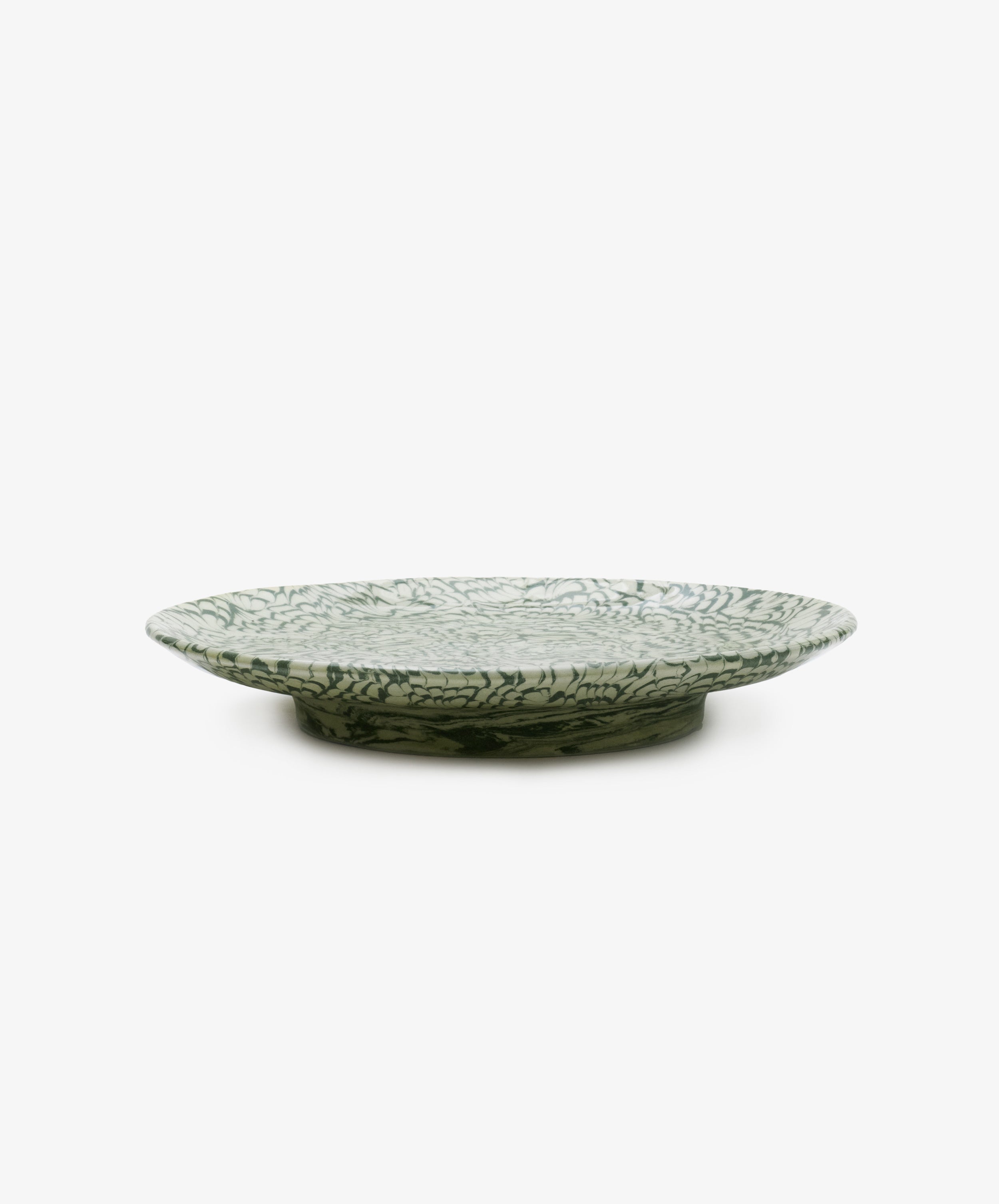 The Celine Serving Platter is a green and white ceramic plate featuring a leaf-like pattern and shown from the side on a plain white background; this handmade serving dish captures the allure of marbled ceramics, making it an elegant Aptware-inspired addition to any table setting.