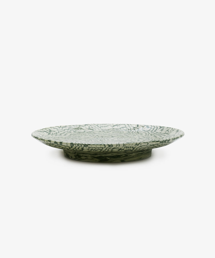The Celine Serving Platter is a green and white ceramic plate featuring a leaf-like pattern and shown from the side on a plain white background; this handmade serving dish captures the allure of marbled ceramics, making it an elegant Aptware-inspired addition to any table setting.
