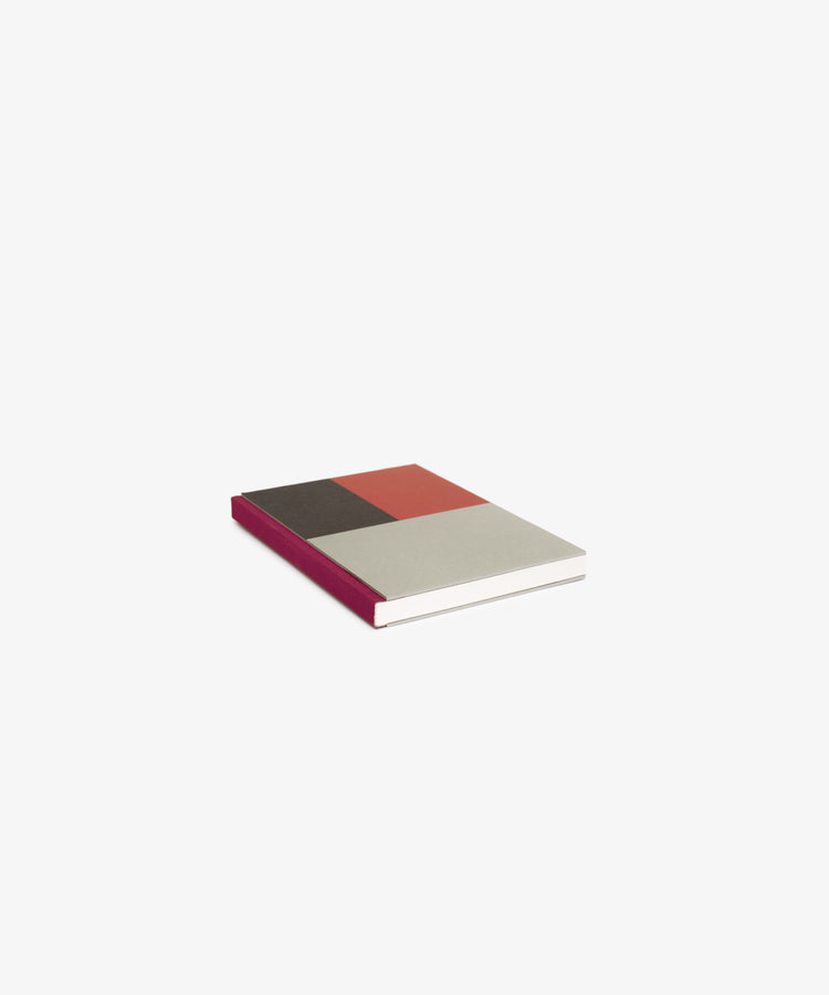The Dreamer's Notebook, featuring a closed multicolored cover with gray, brown, and red sections plus a burgundy spine, rests on a white background—ideal for jotting down thoughts or notes.