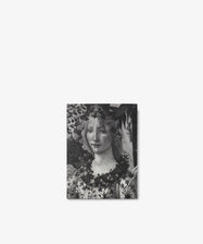 Black and white image of Botticelli, a classical painting reminiscent of Renaissance art, featuring a woman adorned with flowers in her hair and around her neck, set against a leafy background evocative of Primavera.