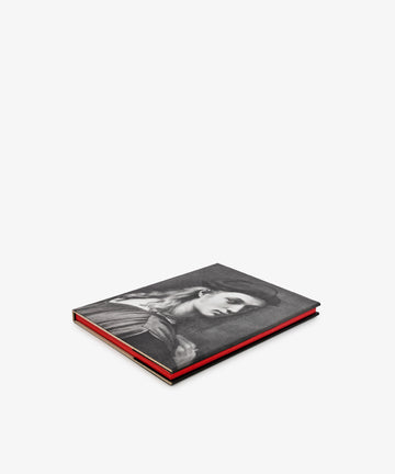 A closed hardcover copy of *Raphael* from the Phaidon Classics series rests on a white surface, its red-edged pages visible and its cover adorned with a black-and-white portrait of a woman—capturing the timeless elegance of High Renaissance masterpieces.