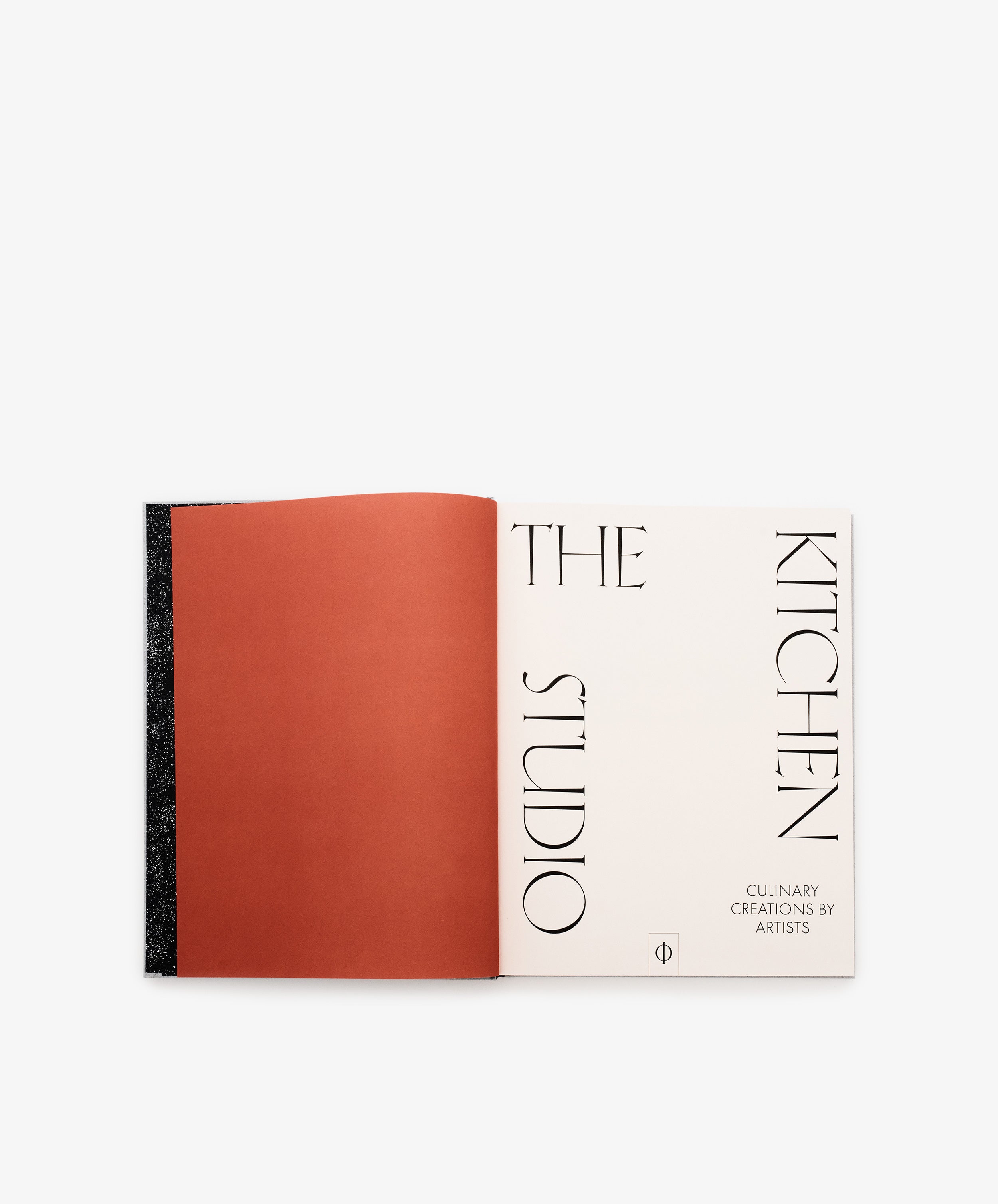 An open book reveals a red left page and a right title page featuring The Kitchen Studio: Culinary Creations by Artists in bold black text—an inventive cookbook that highlights creative recipes and the artistic visions of contemporary creators.