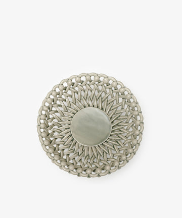 The Remi Footed Bowl features a round, silver-toned design with a woven, spiked pattern radiating from a smooth center, crafted to resemble hand-braided clay for added texture and sculptural appeal.