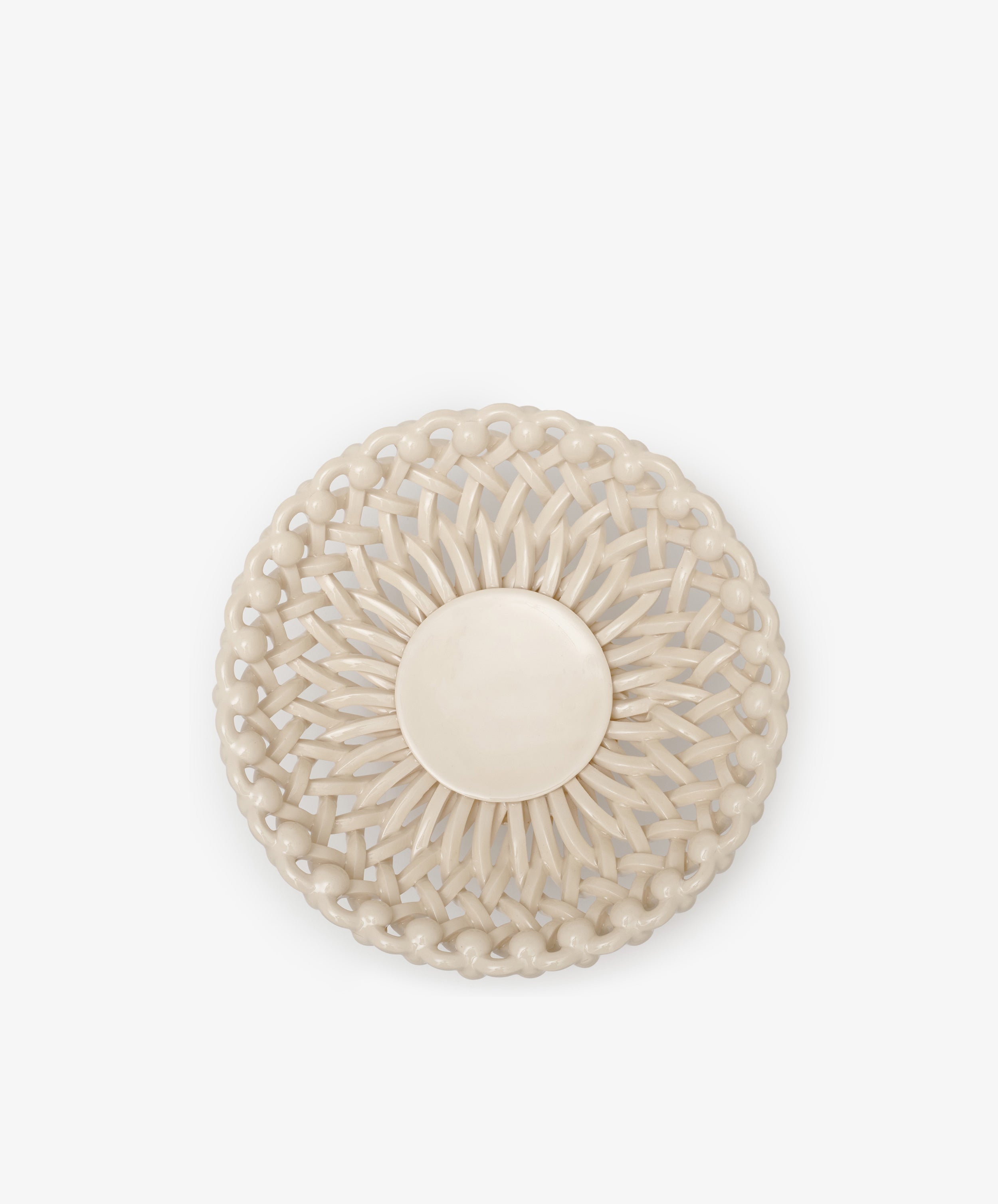 The Remi Footed Bowl is a round, beige, hand-braided clay piece with a solid circular center and symmetrical glossy pattern—an eye-catching sculptural statement, shown against a plain white background.