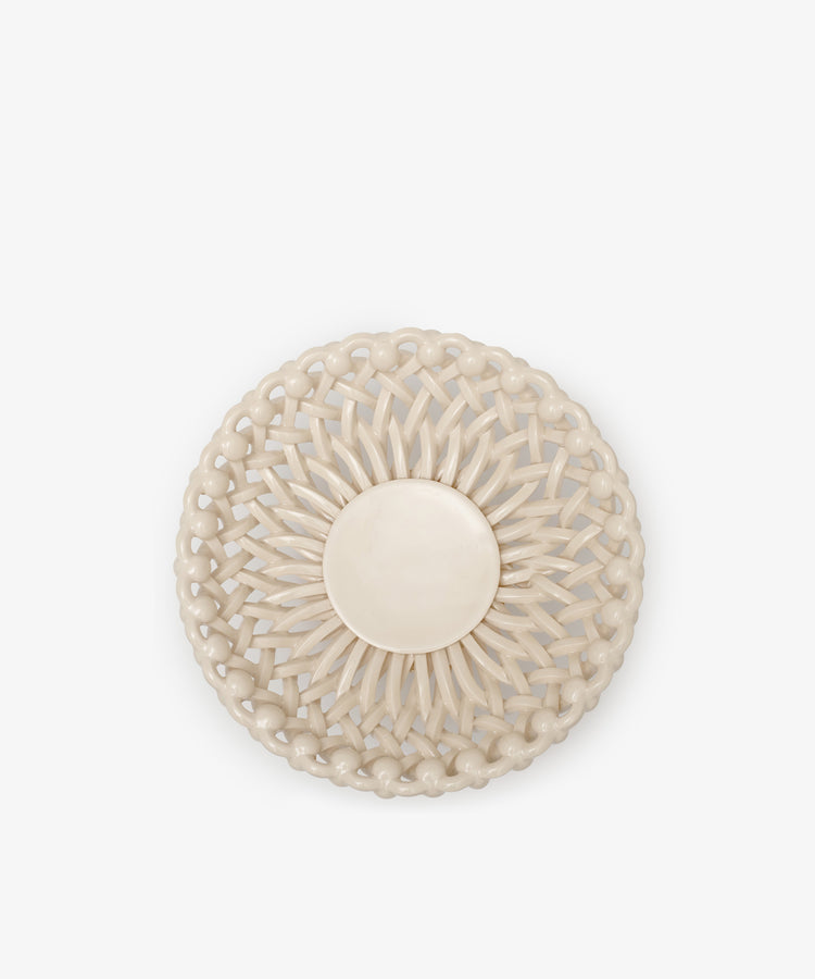 The Remi Footed Bowl is a round, beige, hand-braided clay piece with a solid circular center and symmetrical glossy pattern—an eye-catching sculptural statement, shown against a plain white background.