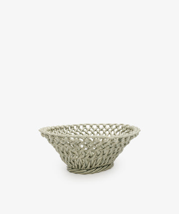 The Remi Decorative Fruit Bowl is a shallow, round woven basket in a light hue, perfect for displaying fruit or adding an artistic touch to any room. Shown on a plain white background.