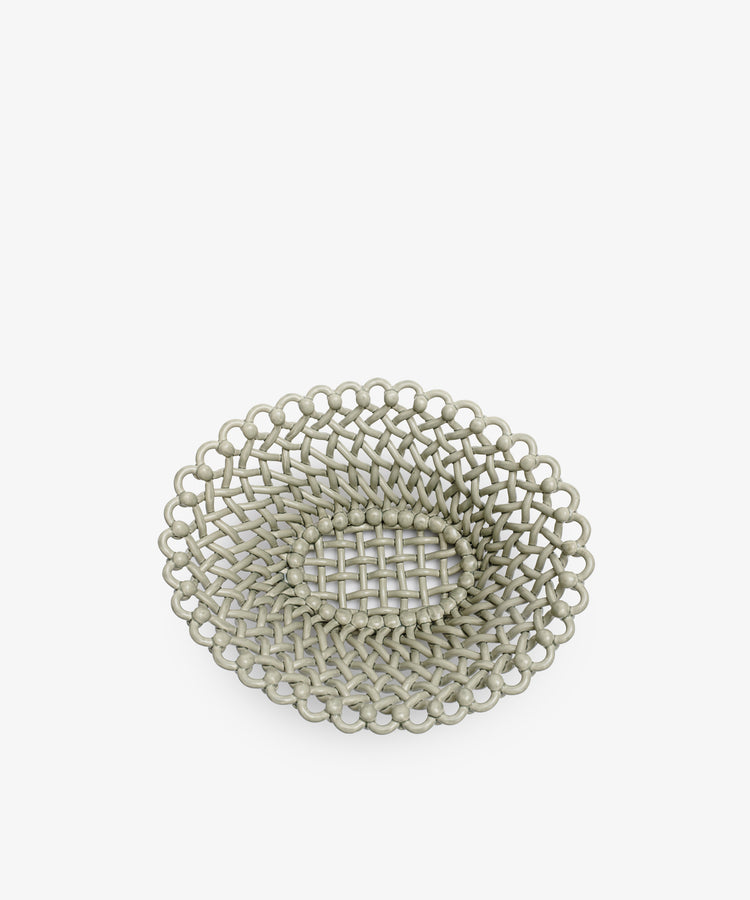 The Remi Decorative Fruit Bowl is a round, shallow, light gray hand-braided clay bowl featuring a circular openwork pattern, shown on a white background.