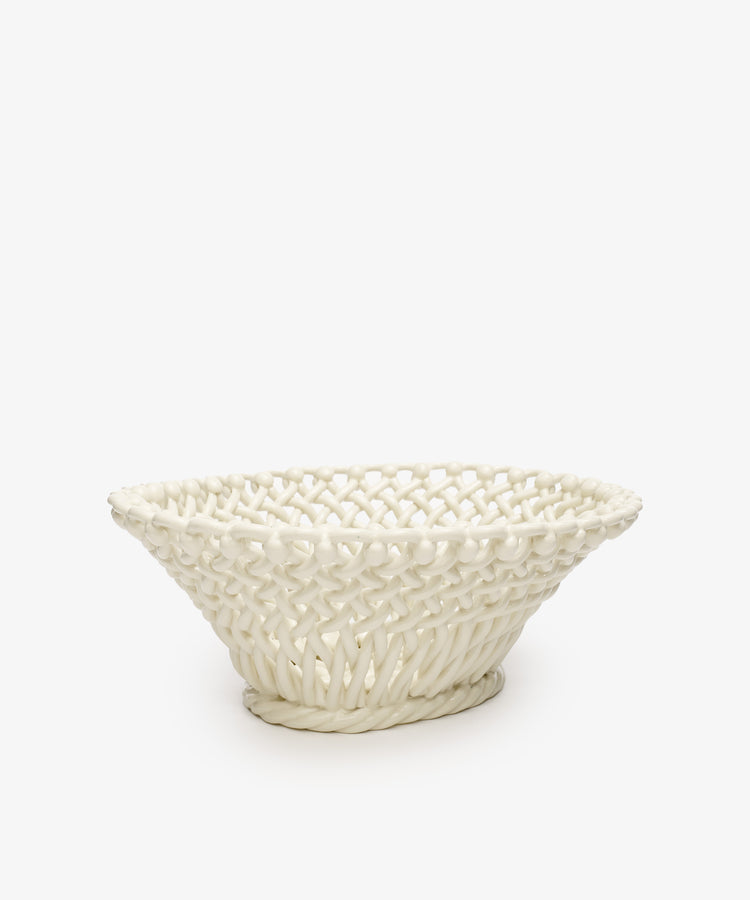 The Remi Decorative Fruit Bowl is a white glazed ceramic basket featuring a hand-braided woven pattern and wide, shallow shape, perfect for displaying fruit. Shown against a plain white background.