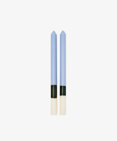 Two Highbury Candles with a blue body and black and white color blocks at the base stand side by side on a white background. These hand-poured sculptural candles bring modern style to any space.