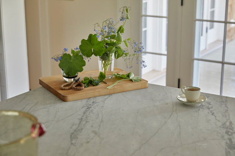 marble kitchen table with flowers in cups and espresso cup on table