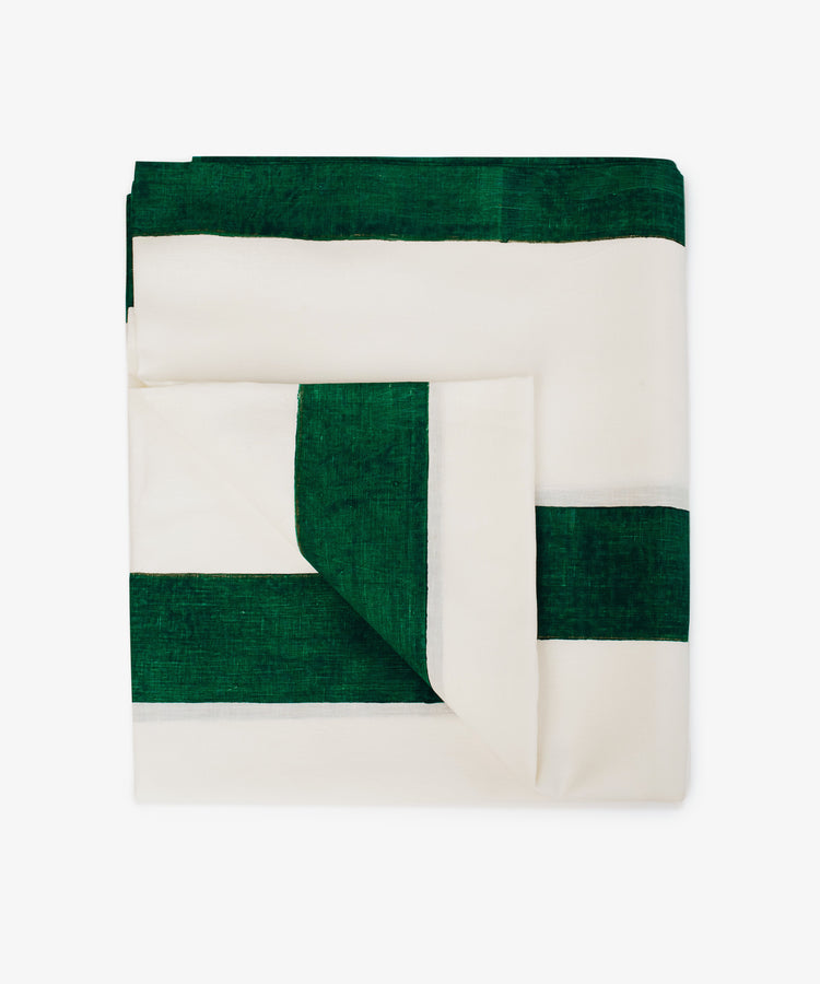 The Riga Tablecloth, hand-printed with green stripes, is artfully folded and displayed on a plain white background to showcase its artisanal charm.