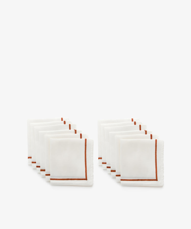 Set of white linen napkins with rust stripe detail.