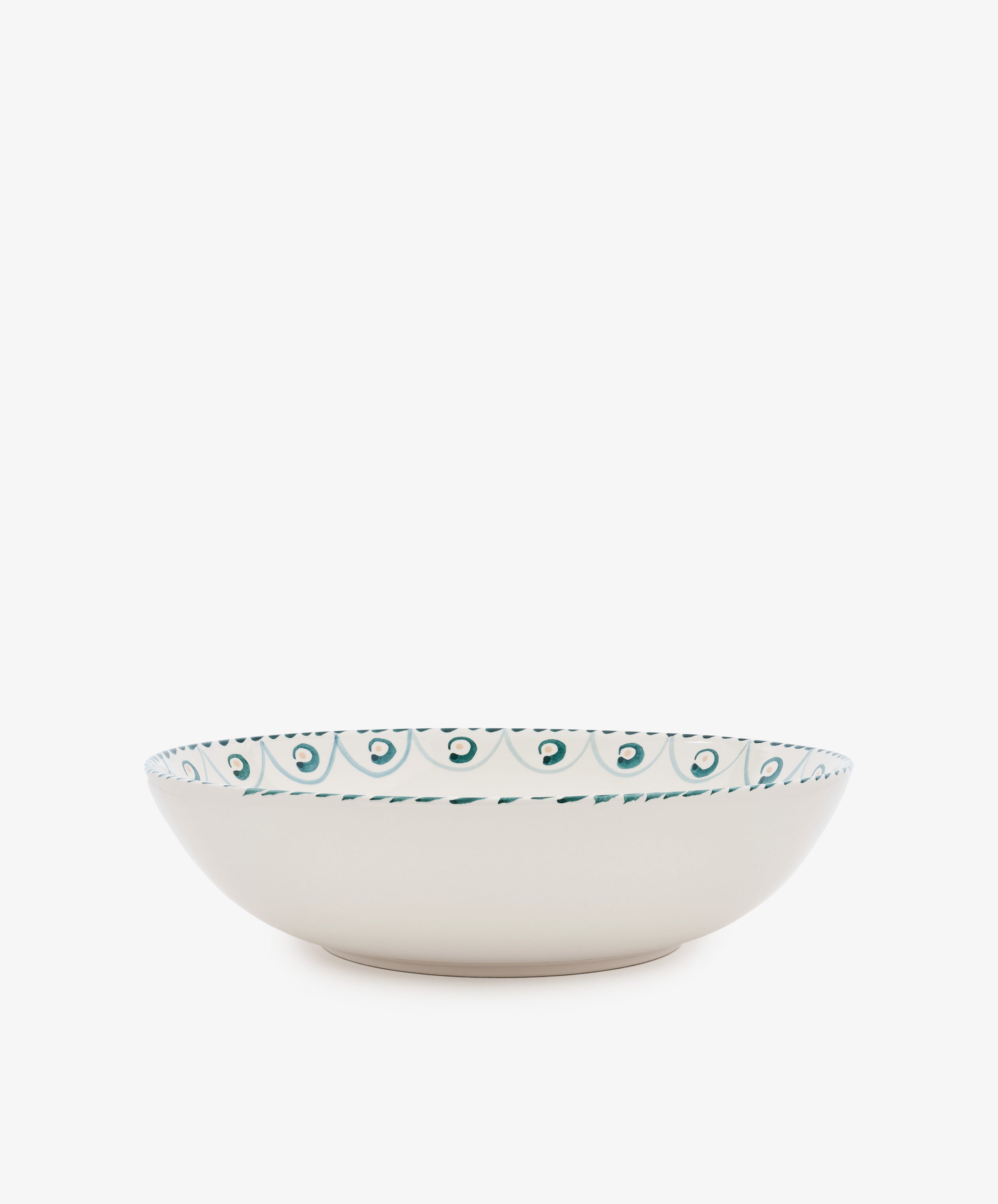 The Ottoline Serving Bowl is a shallow, cream-colored ceramic bowl with a teal and green patterned rim inspired by Tess Newall’s hand-painted designs, shown against a plain white background.
