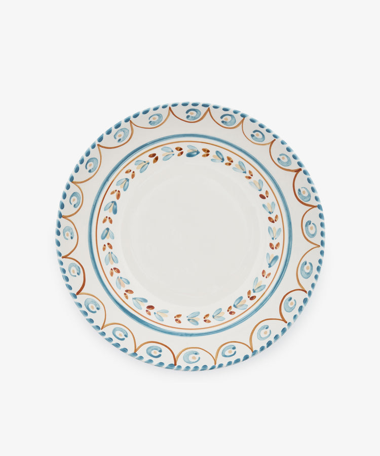 The Ottoline Serving Bowl is a round ceramic piece with a white center and blue, orange, and brown patterned borders inspired by Italian majolica.