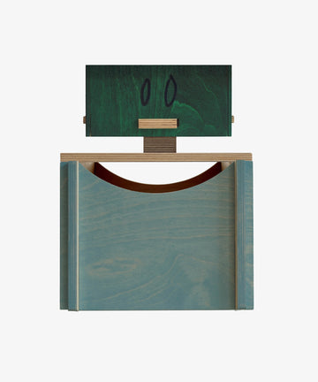 The Milo Keepsake Box by PORTA House of RoRo is a geometric wooden sculpture with a blue base, green block adorned with two black ovals, and a horizontal wood piece—like a modular keepsake box for your modern puzzle treasures.