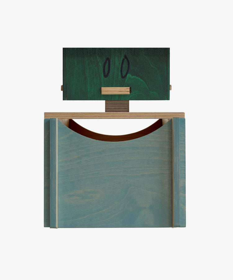 The Milo Keepsake Box by PORTA House of RoRo is a geometric wooden sculpture with a blue base, green block adorned with two black ovals, and a horizontal wood piece—like a modular keepsake box for your modern puzzle treasures.
