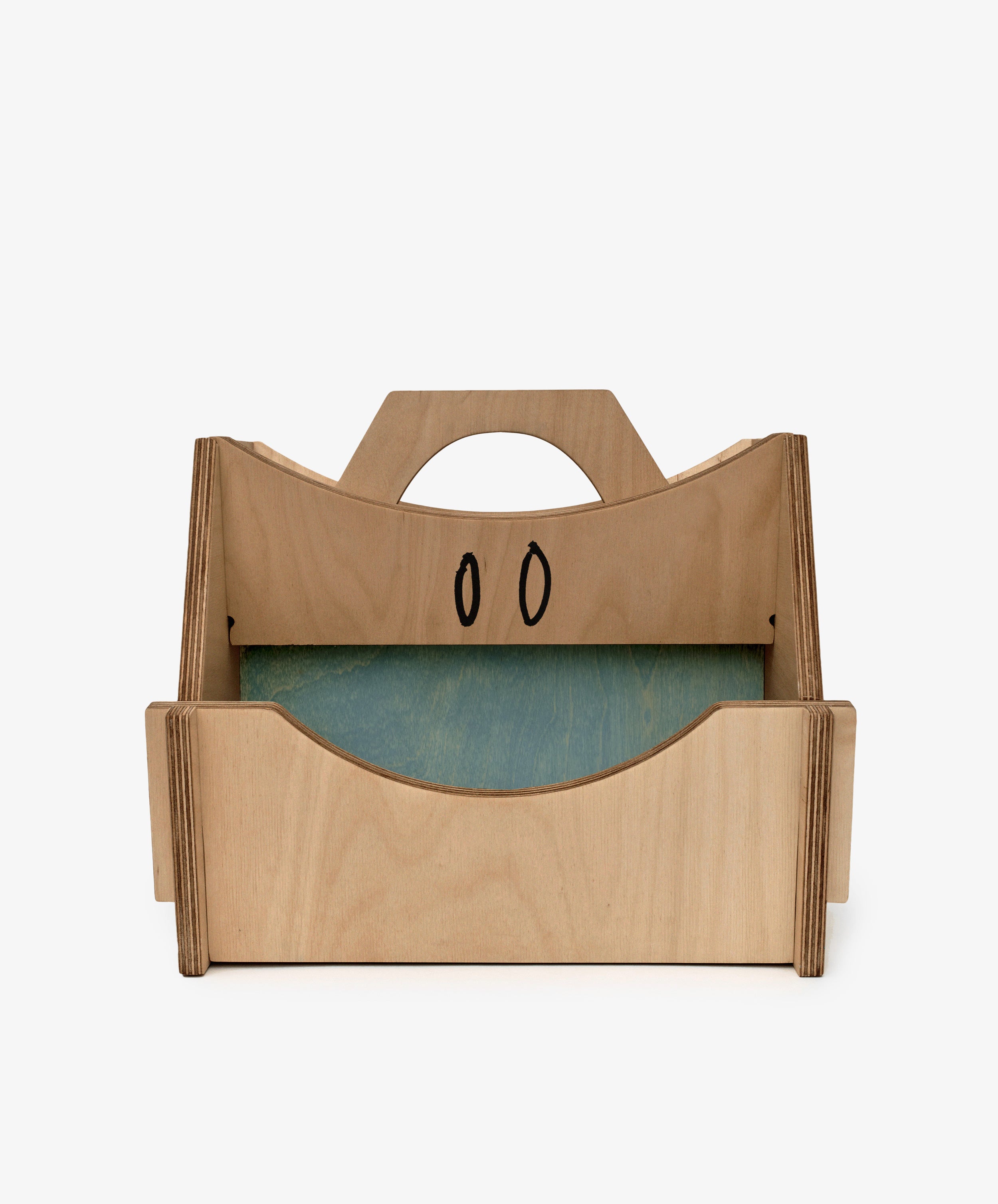 The Casper Caddy by House of RoRo is a kids wooden storage caddy with a handle, side panels, a green bottom, and two black oval designs on the back panel.
