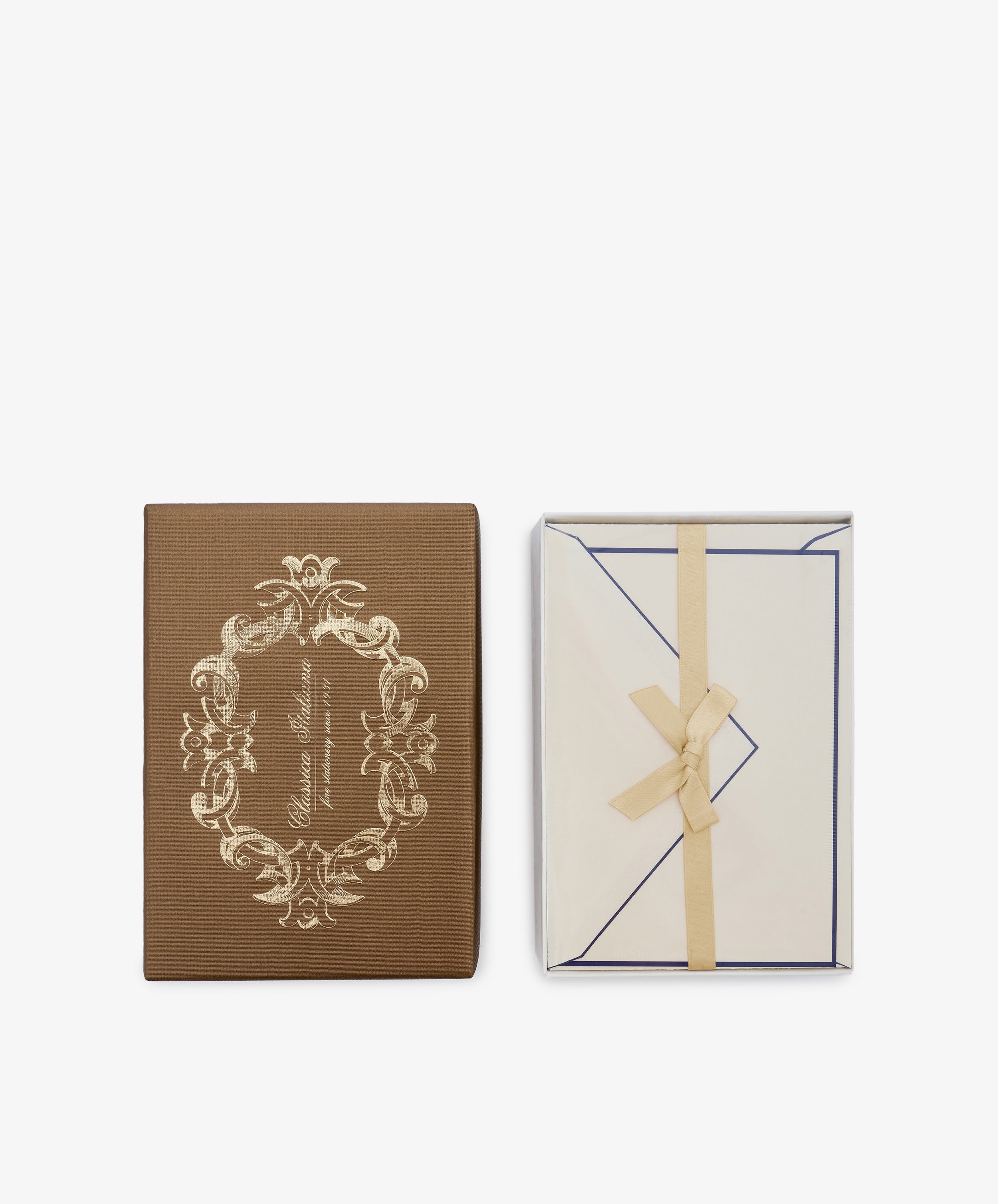 A brown decorative box with gold detailing sits beside an open box revealing the Bordered Correspondence Card & Envelope set of 25, featuring cream-colored cotton paper stationery tied with a beige ribbon—perfect for elegant wedding thank you cards.