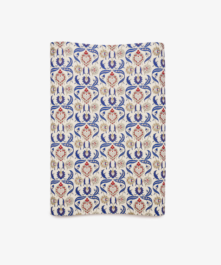 Arabesque Gift Wrap featuring a rectangular textile design with an ornate repeating pattern in red, blue, and beige on a cream background, showcasing symmetrical floral motifs and abstract Arabesque elements.