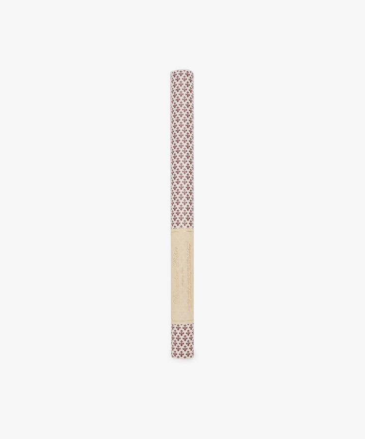 A rolled sheet of Lilies Gift Wrap featuring a red floral design, wrapped in a beige label, stands upright on a white background.