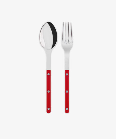 The Bistrot Serving Set, featuring a stainless steel spoon and fork with red handles and silver rivets in Parisian bistro style, is arranged side by side on a white background.