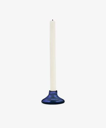 The Lucien candleholder, Large, crafted from handblown recycled blue glass, holds a white taper candle and is set against a plain white background.