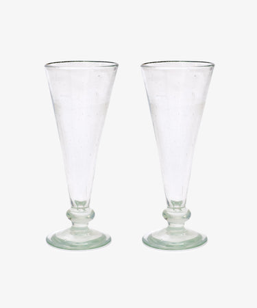 A set of six Elodie Champagne Glasses, featuring clear, tall handmade stems with round bases, are displayed side by side against a plain white background.