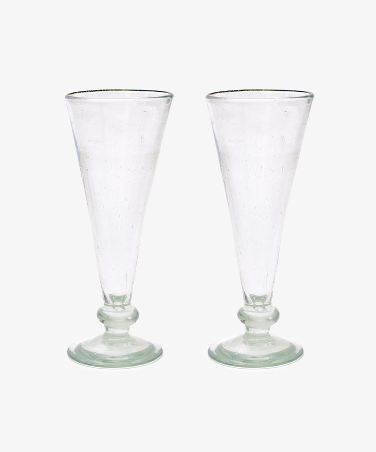 A set of six Elodie Champagne Glasses, featuring clear, tall handmade stems with round bases, are displayed side by side against a plain white background.