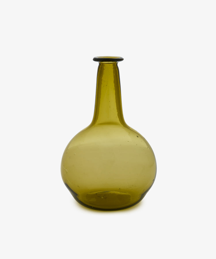 The Elodie Bedside Carafe and Glass Set is an olive-green, hand-blown glass bottle featuring a round bottom and a long, narrow neck—ideal as a nightstand or bedside water carafe—shown against a plain white background.