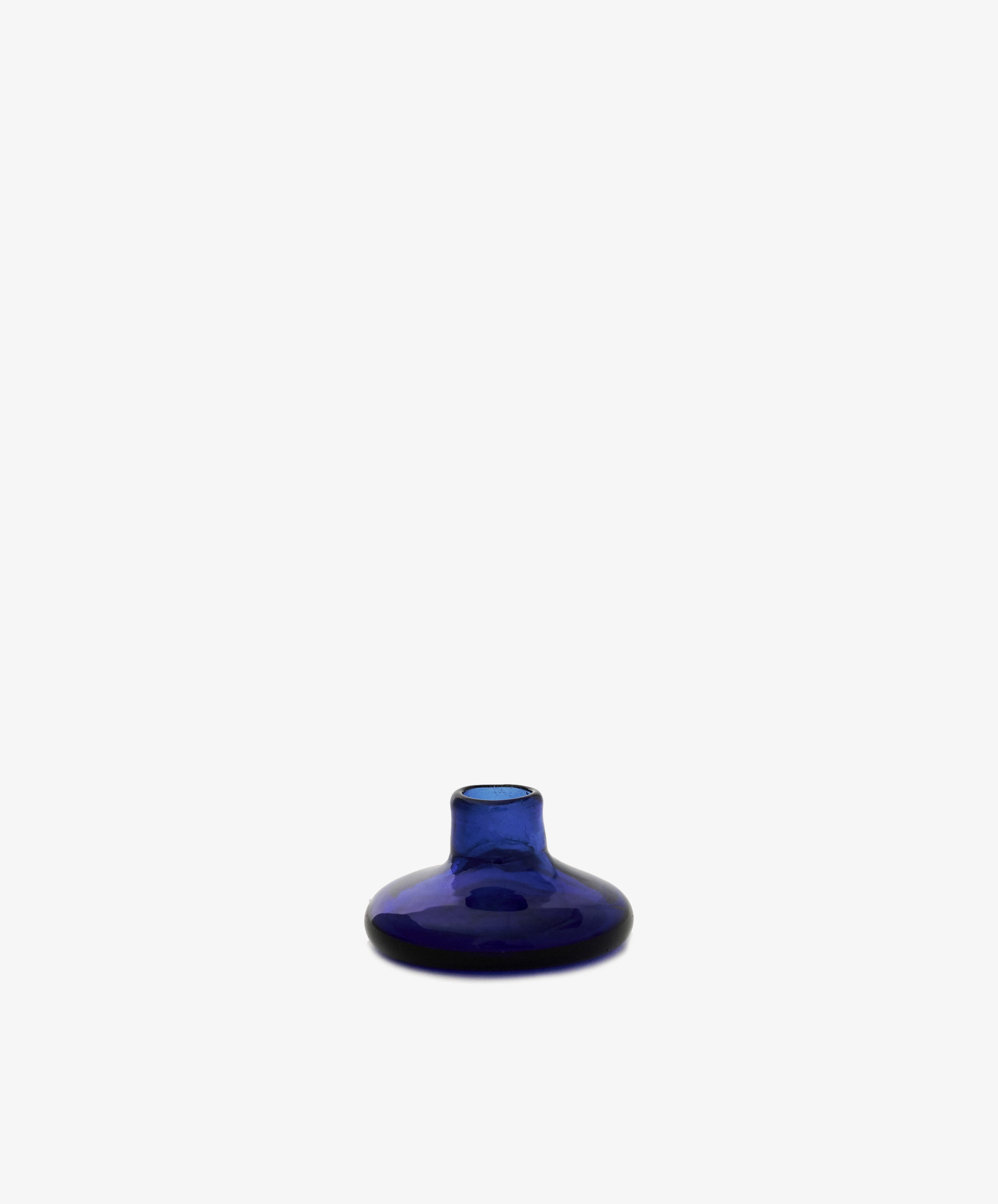The Lucien bubble candleholder, Small, is a cobalt blue, round glass piece with a narrow neck made from recycled glass. Its design evokes handmade Moroccan candle holders and is shown against a plain white background.