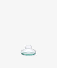 The Lucien candleholder, a small clear glass piece with a wide base and narrow neck inspired by Moroccan handblown design, is displayed against a plain white background.