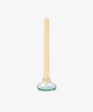 The Lucien candleholder, crafted from clear handblown Morocco recycled glass, displays a single beige taper candle standing upright against a plain white background.
