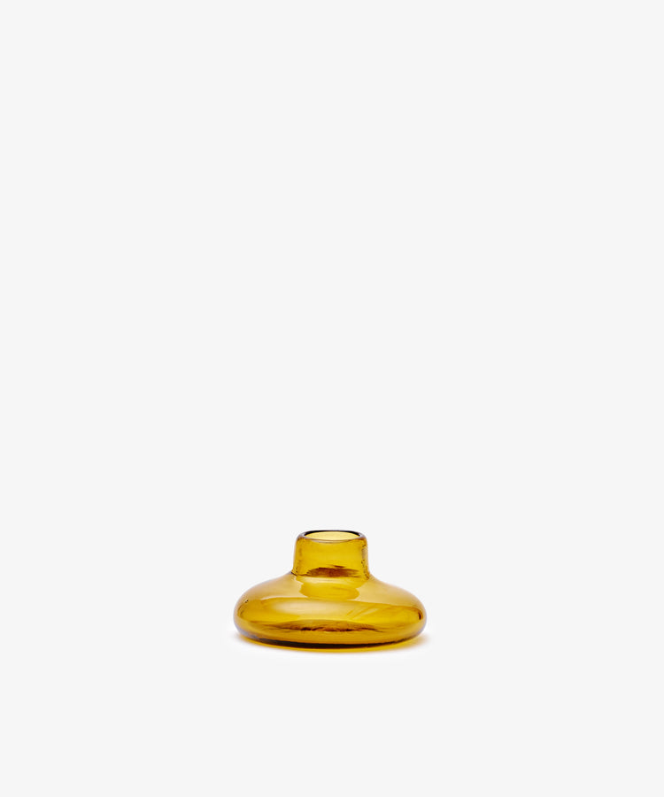The Lucien candleholder is a small, round, amber glass vase with a short neck, handblown in Morocco from recycled glass candle holders and shown against a plain white background.