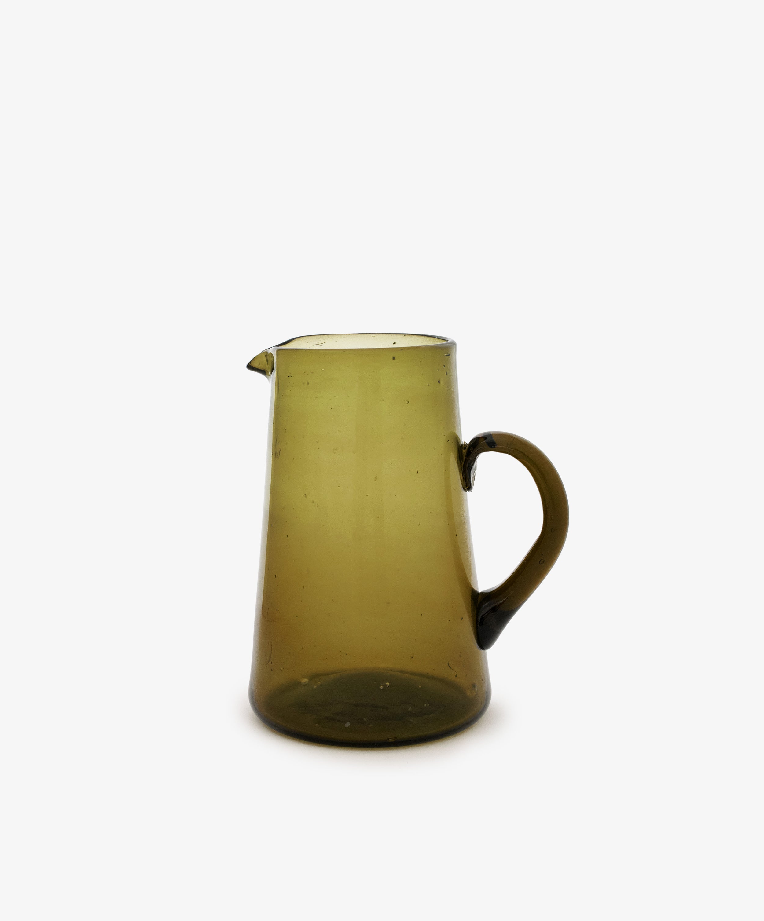 The Elodie Pitcher is a handblown, translucent olive-green glass pitcher from Damascus, featuring a handle and spout, shown against a white background.