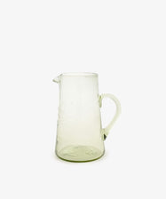 The Elodie Pitcher is a handblown Damascus glass piece with a handle and small spout, ideal for adding Mediterranean charm to your decor. Shown against a plain white background.