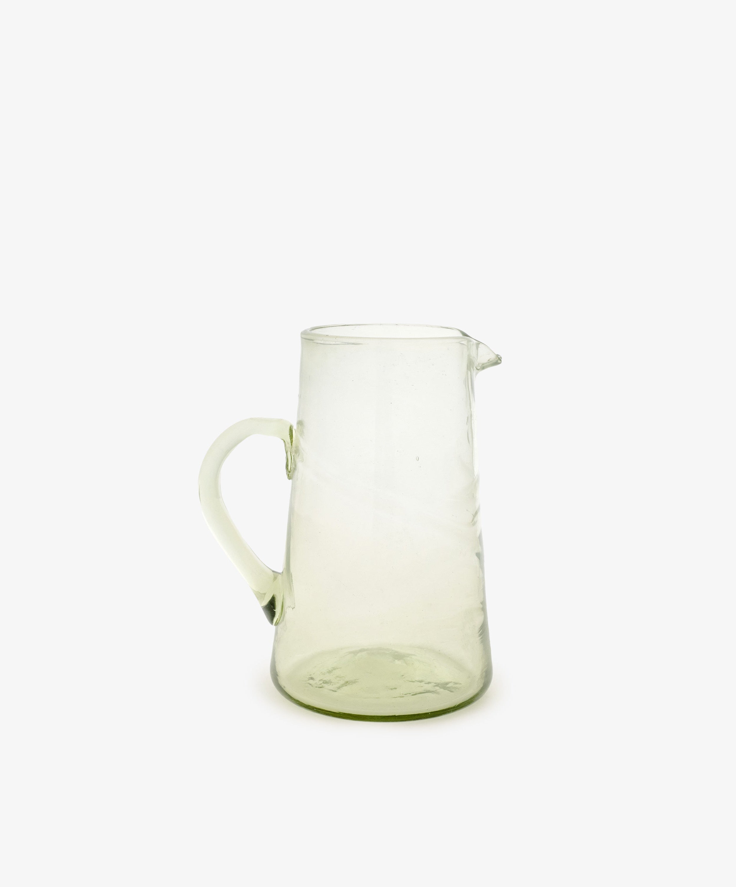 The Elodie Pitcher, with its clear glass and subtle green tint, features a handle and spout. Shown against a plain white background, it evokes handblown Damascus style—an elegant accent for Mediterranean decor.