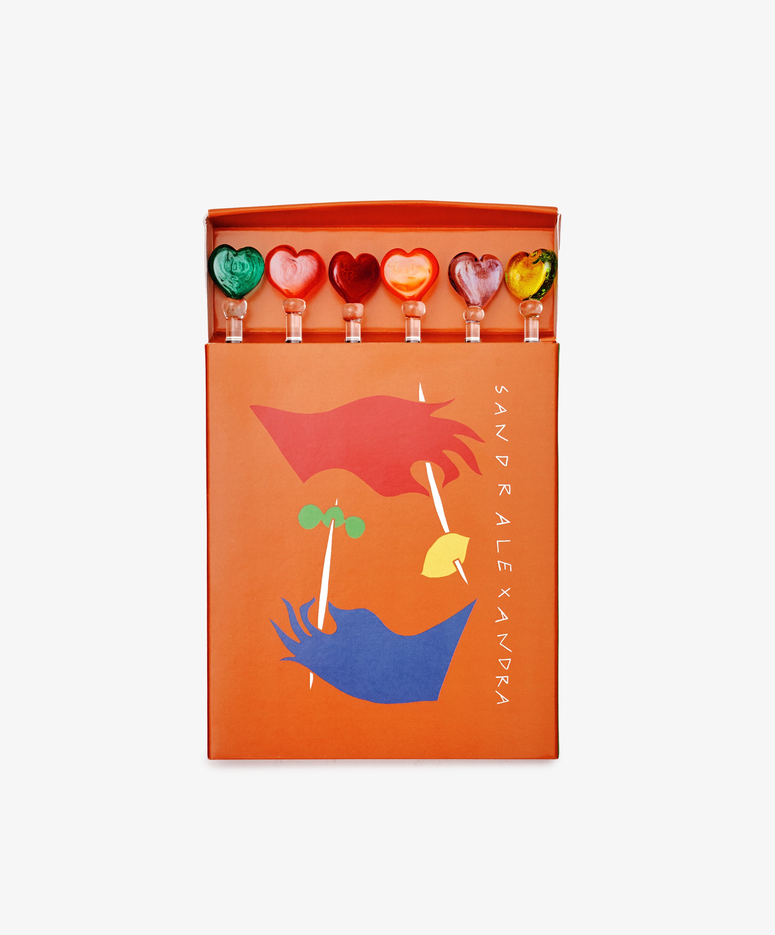 The Heart Cocktail and Nibble Sticks Set includes six heart and fruit-shaped sticks in a bright orange box with abstract face art—ideal as playful drink accessories or cocktail sticks.