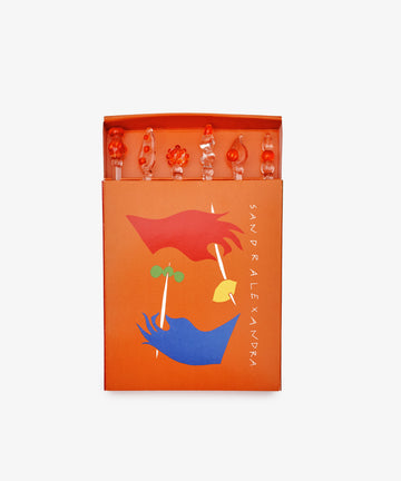 The Festa Cocktail and Nibble Sticks set includes six uniquely shaped decorative picks, presented in an orange box with abstract face artwork and 