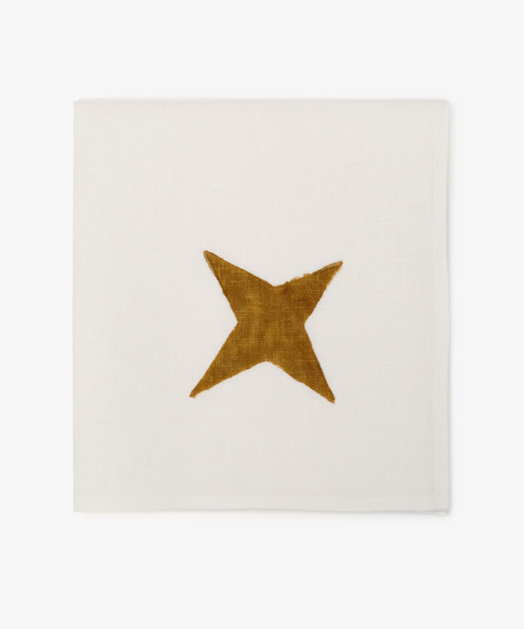 The Nova Napkin Set of 6 features ivory linen napkins, each hand block-printed with a simple gold star design in the center.